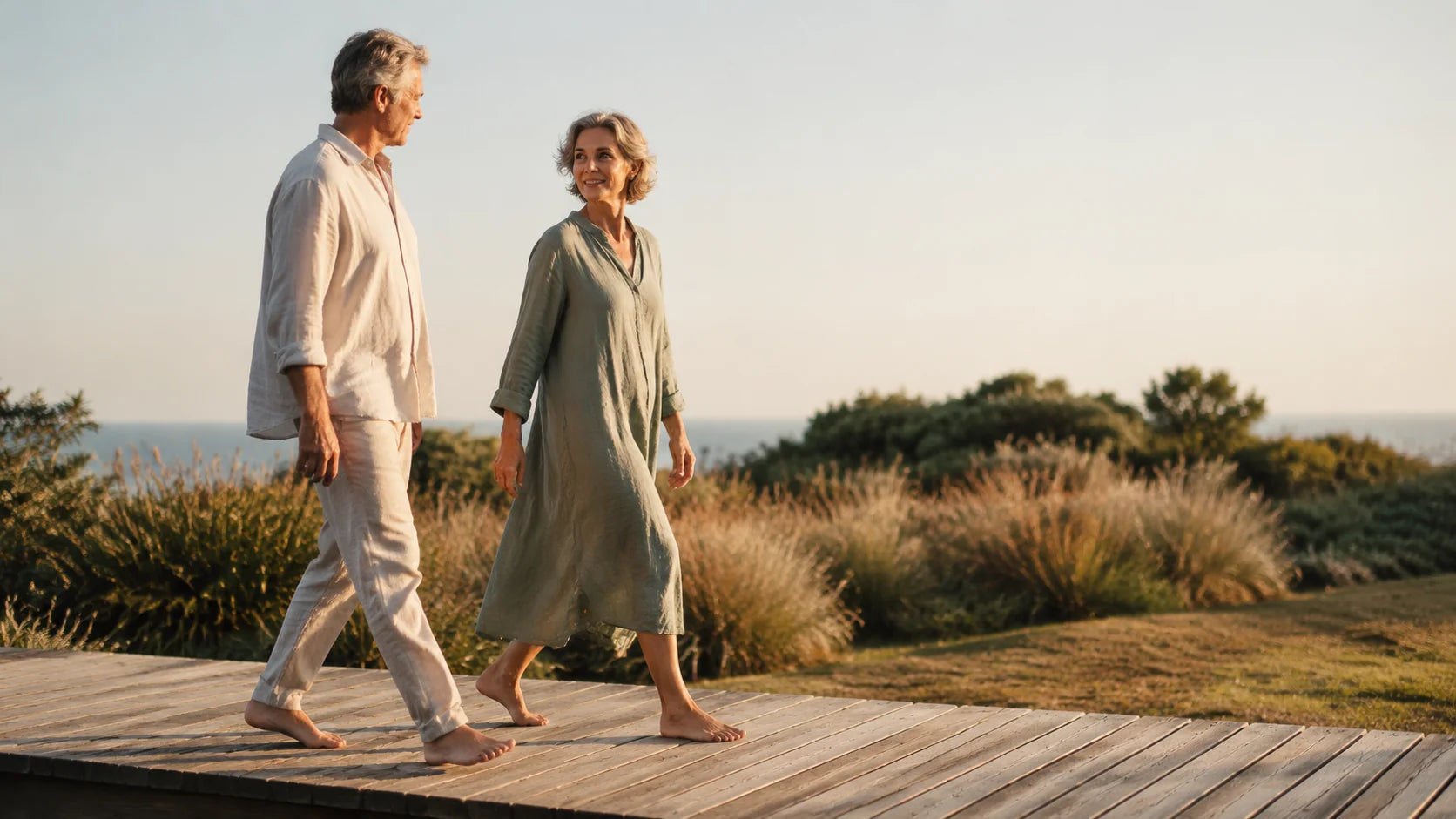 Older man and woman walking barefoot together on a wood deck, daylight, no clinical context