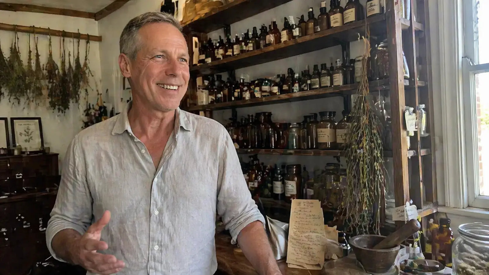 Alan Meyers, a silver-haired man in his late 50s, standing at a wooden apothecary workbench in his Portland practice.