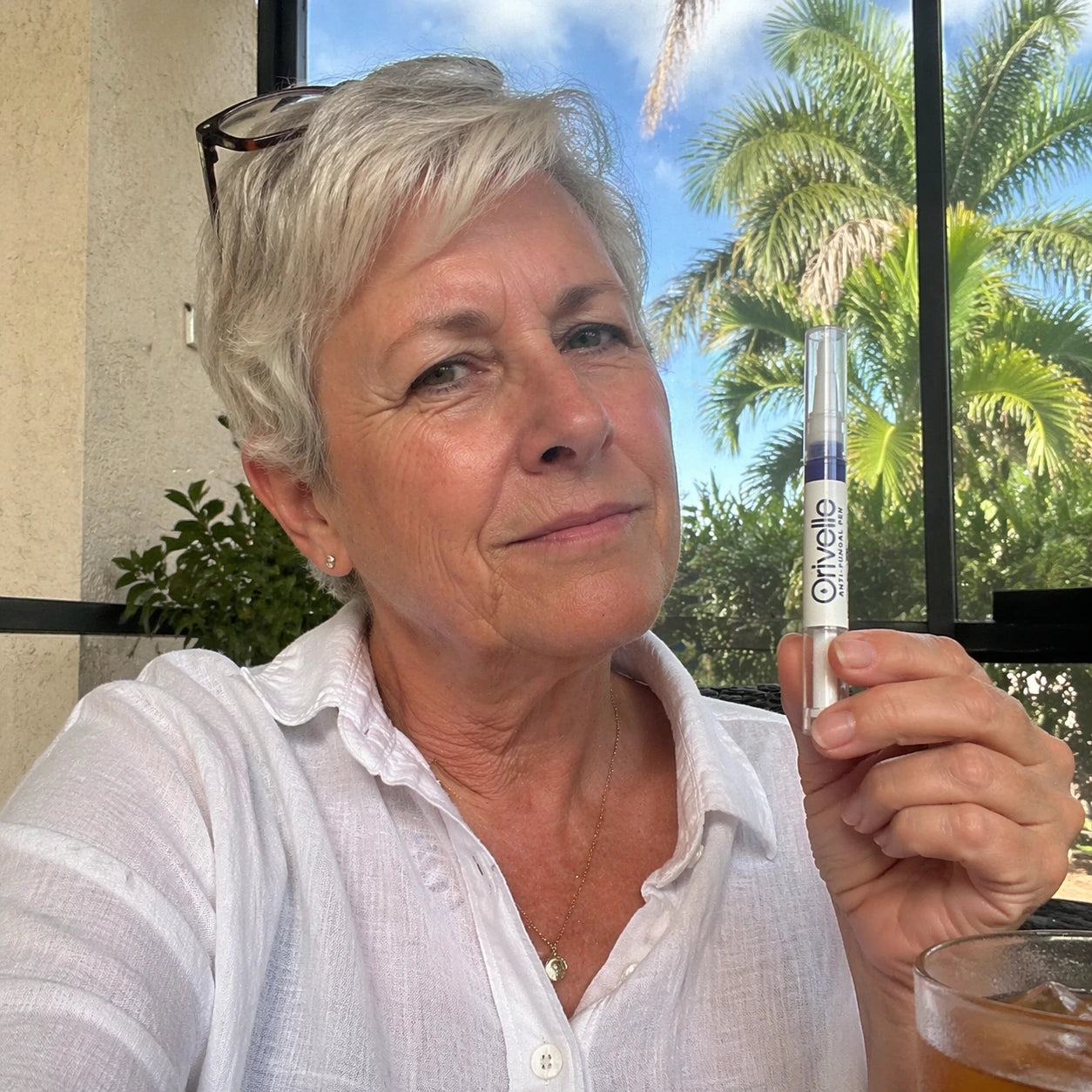 Patricia, a 64-year-old retired pediatric nurse from Sarasota, FL, in a candid editorial patio portrait with a wry, skeptical expression.