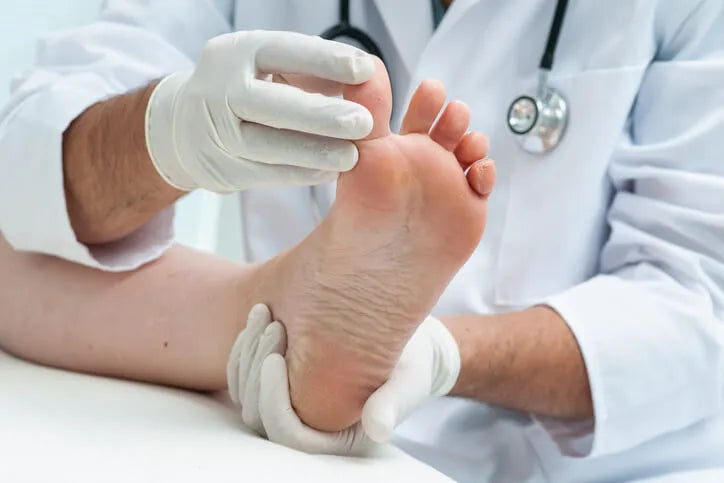 Medical professional in gloved hands examining a foot.
