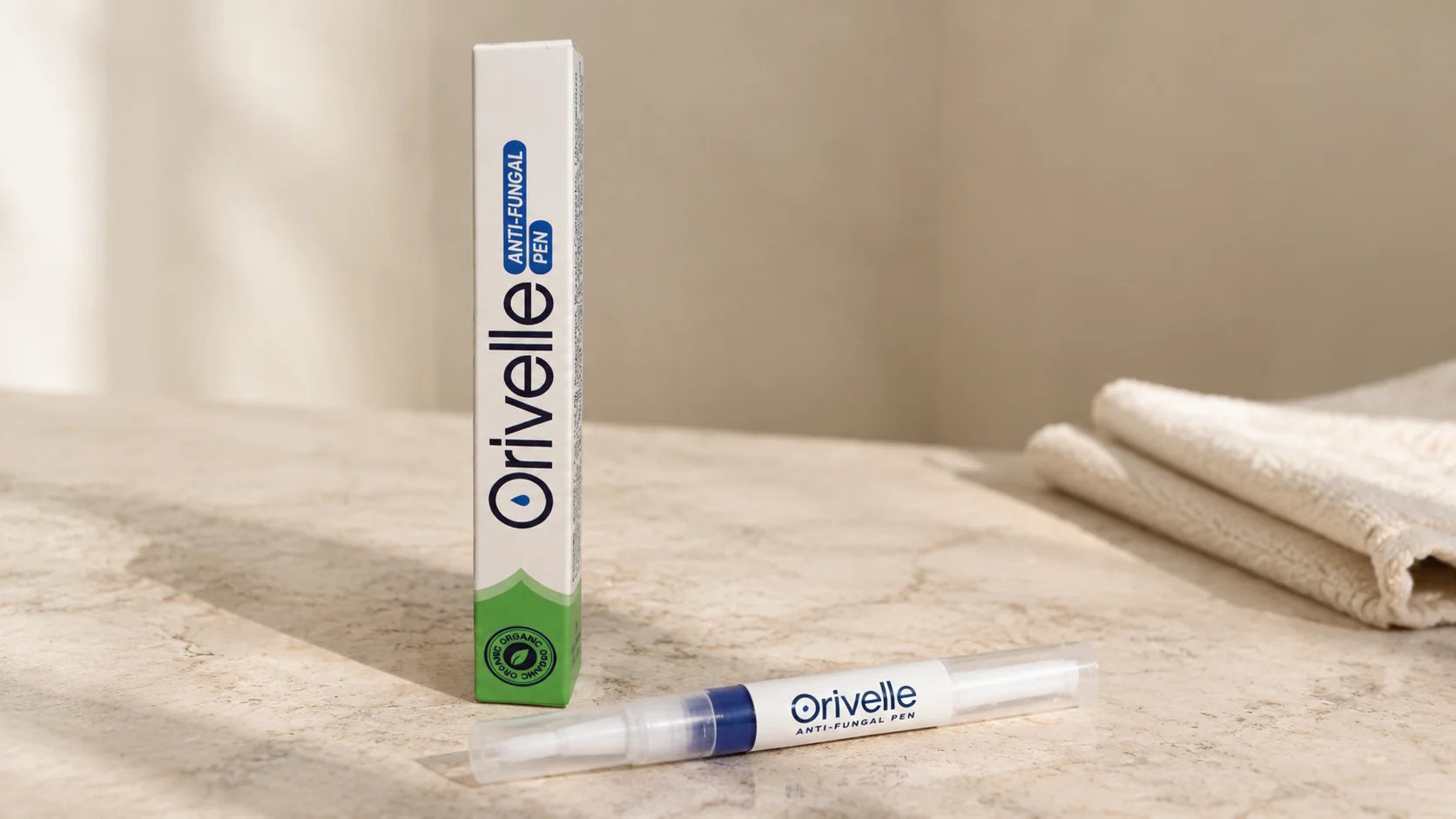 Clean product shot of the Orivelle anti-fungal pen and box on a soft beige marble surface, daylight, no marketing graphics
