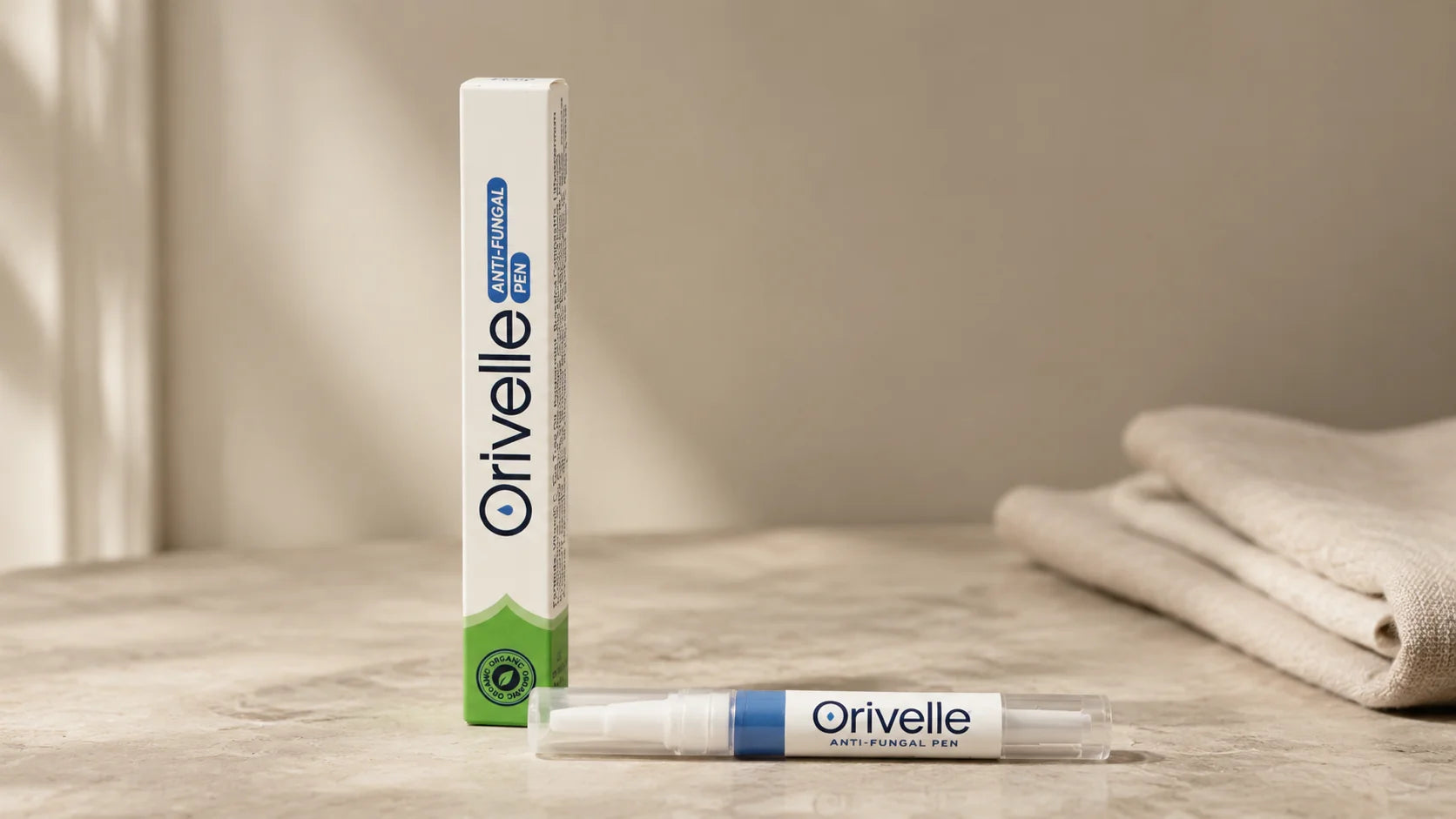 Clean product shot of the Orivelle anti-fungal pen and box on a soft beige marble surface, daylight, no marketing graphics